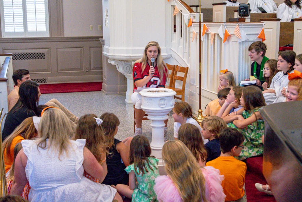 woman speaking to group of children with microphone