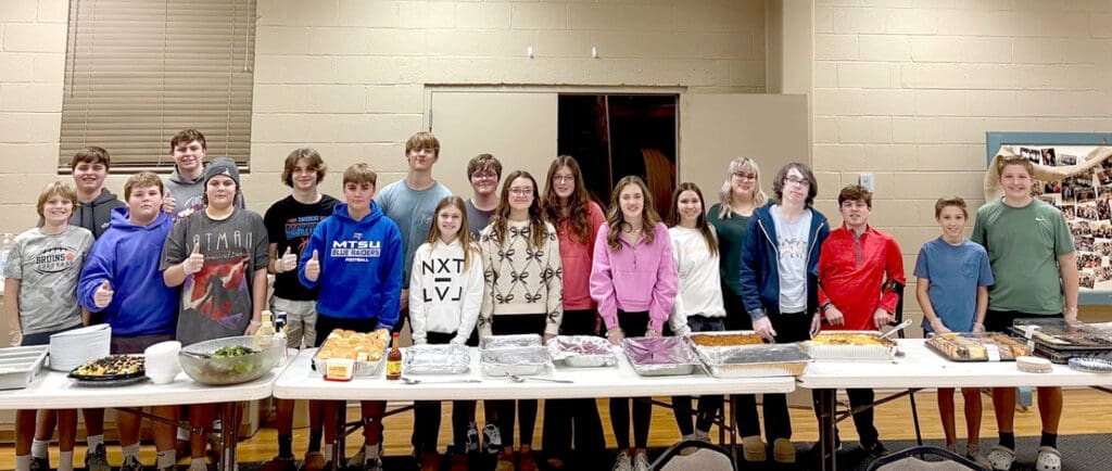 group of children standing at long table